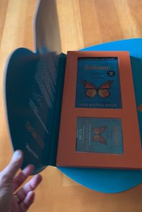 Monarch butterfly box open with book and seed pack inside.